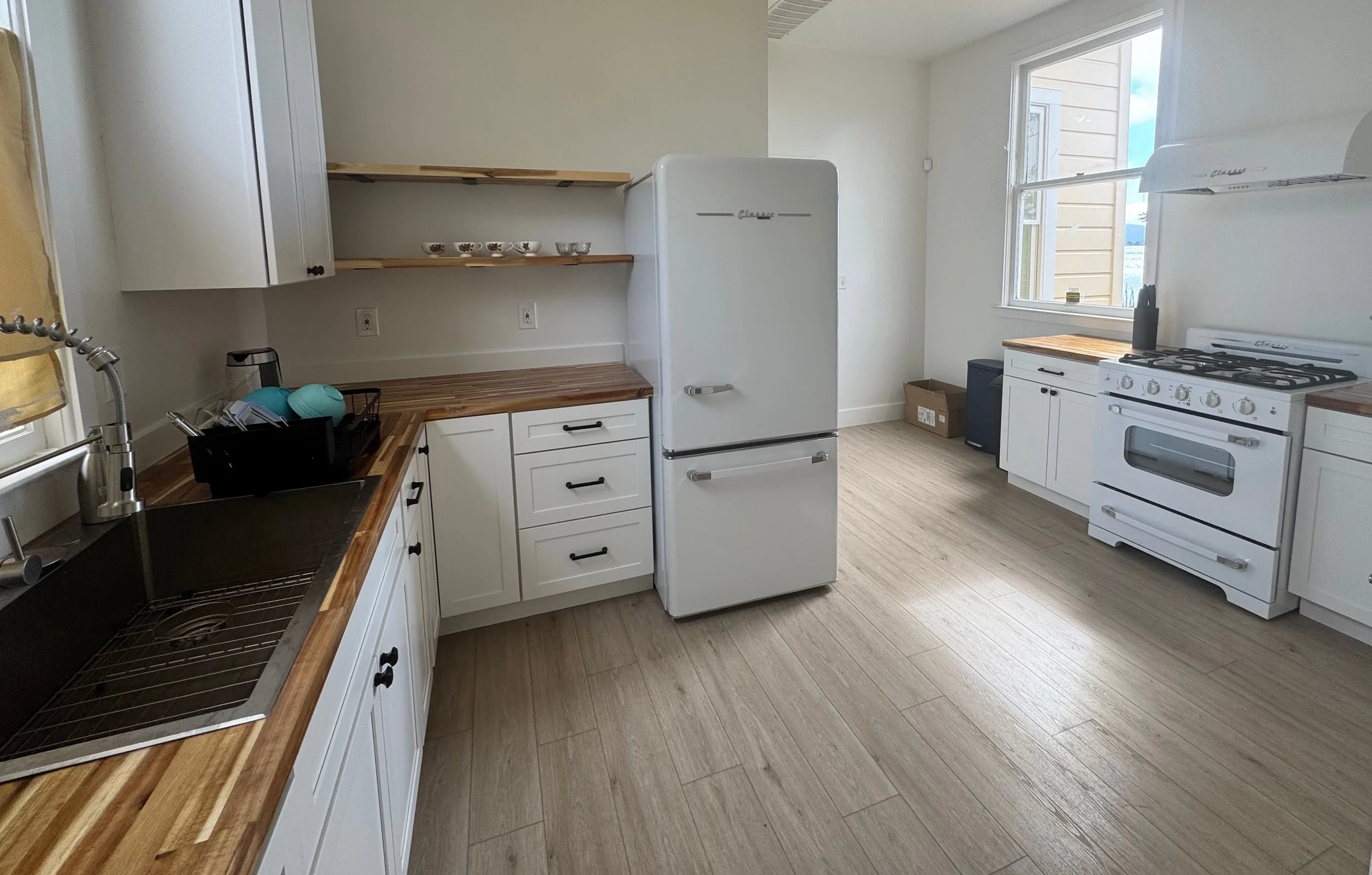 A beautifully remodeled kitchen with white cabinets and butcher block countertops