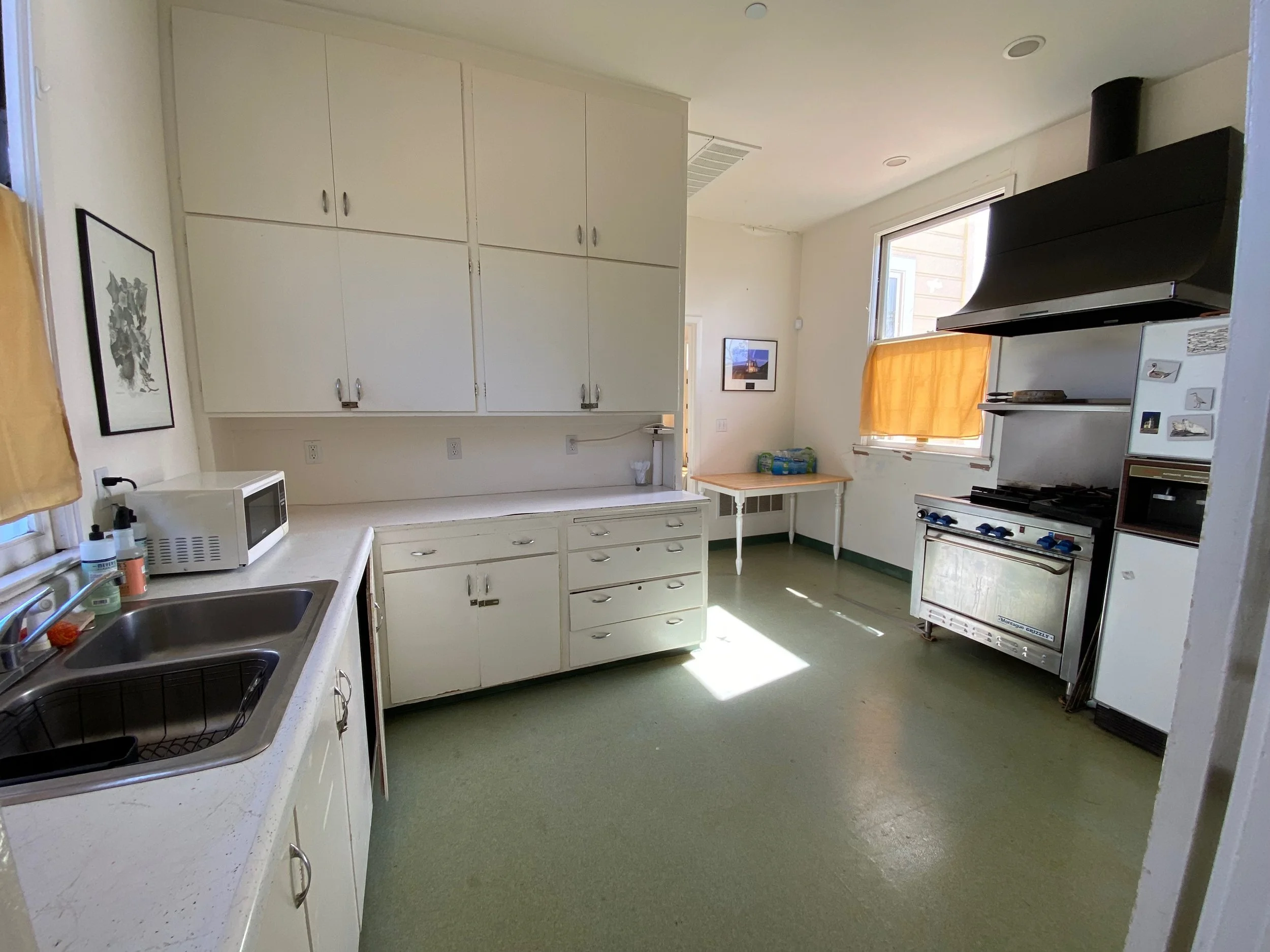 Kitchen before remodel — old cabinets, green floor, dated appliances